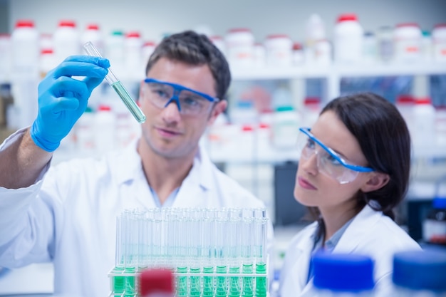 Smiling chemist holding test tube containing liquid