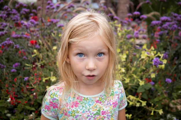 Smiling child girl blonde on a background of flowers