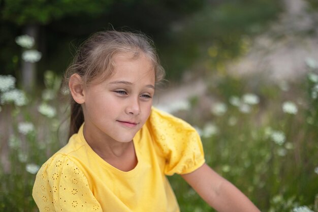 Smiling child girl wear yellow dress posing outdoor at nature background Looking at camera Childhood