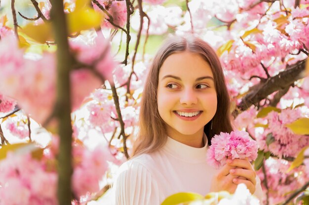 Smiling child at sakura flower bloom in spring