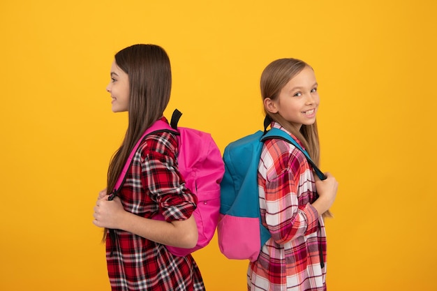 Smiling children in casual checkered shirt carry backpack september