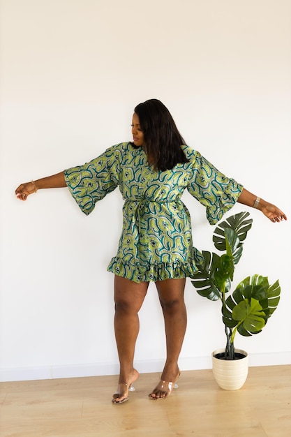 Smiling confident african american young woman wears stylish dress standing over white background in room inclusion and diversity concept