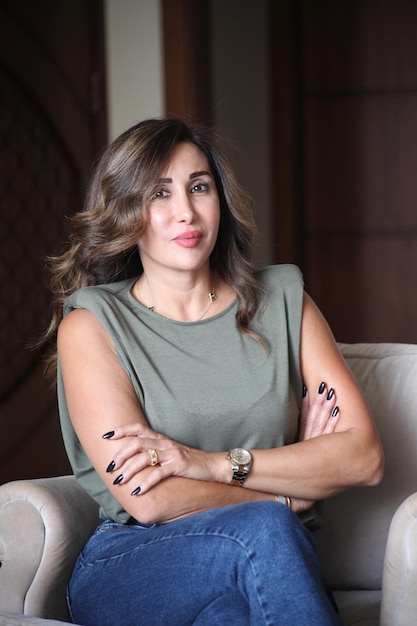 Smiling confident businesswoman posing with arms folded sitting on couch