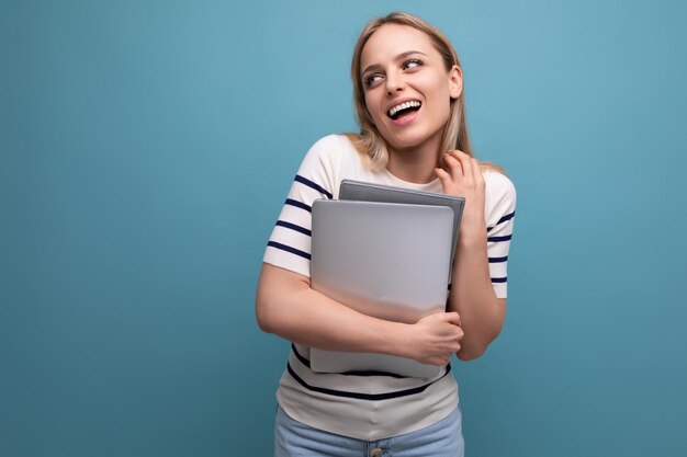 Smiling confident young business woman with a laptop in her hands on a blue isolated background with