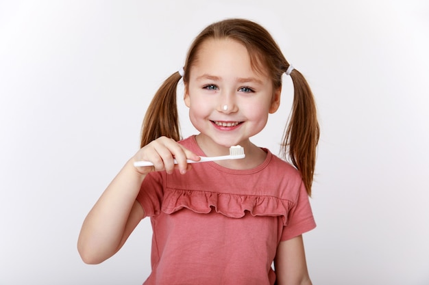 Smiling contented little girl while brushing teeth