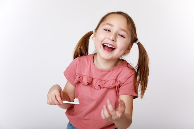 Smiling contented little girl while brushing teeth