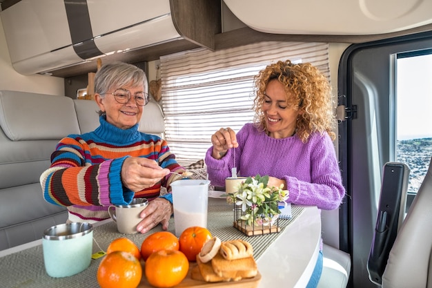 Smiling couple of caucasian women sitting inside a camper van motor home relaxing with a herbal the Lifestyle and travel modern people vacation journey concept