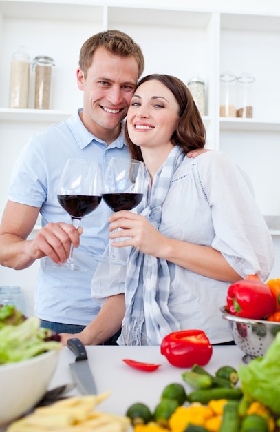 Photo smiling couple drinking wine while cooking