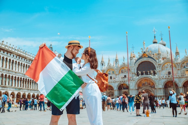 Smiling couple holding italian flag venice central square san marco copy space