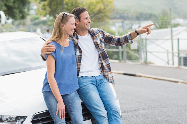 Smiling couple leaning on the bonnet 