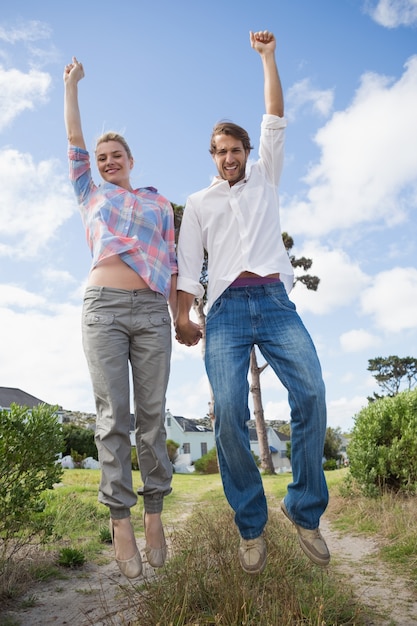 Smiling couple leaping outside together in their garden