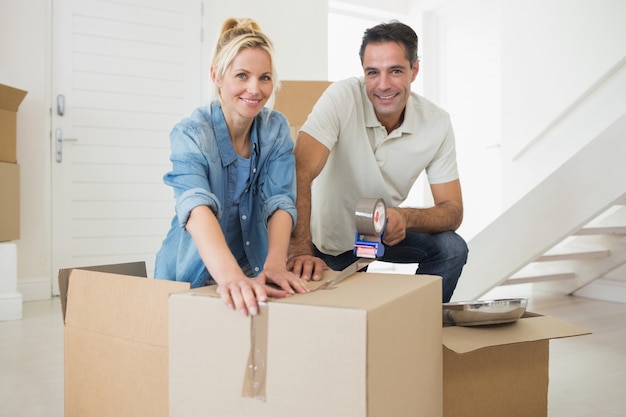 Smiling couple packing boxes in a new house