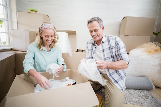 Smiling couple packing mug in a box at home