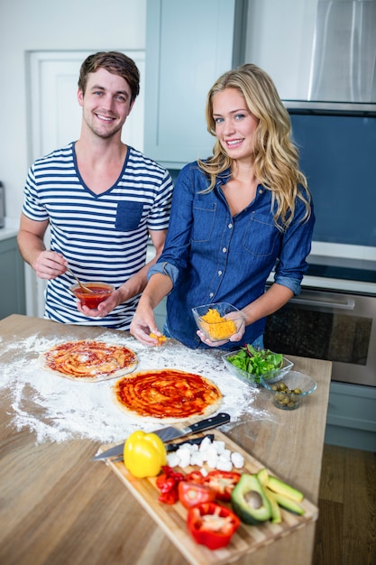 Smiling couple preparing pizza in the kitchen