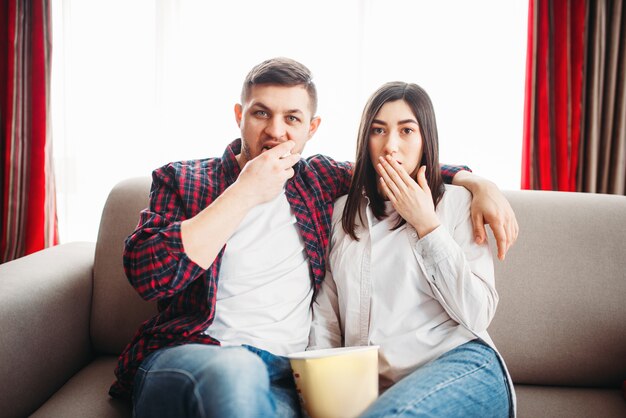 Smiling couple sitting on couch and watch tv