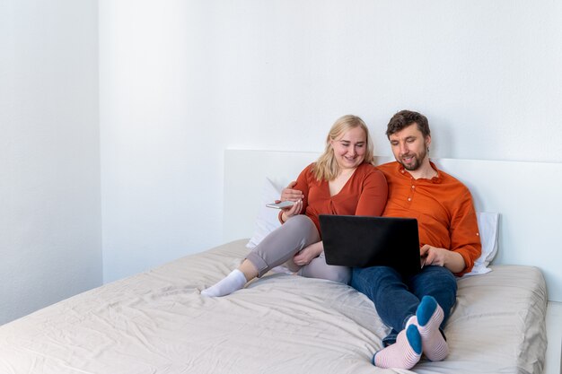 Smiling couple using laptop and smartphone together