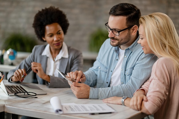 Smiling couple using touchpad while having a meeting with their financial advisor in the office