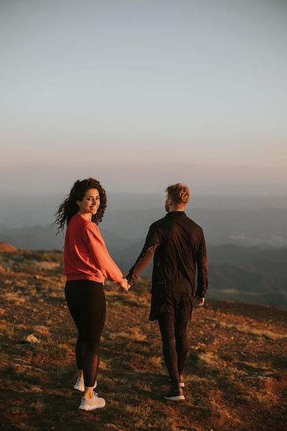 Smiling couple walking over green hills