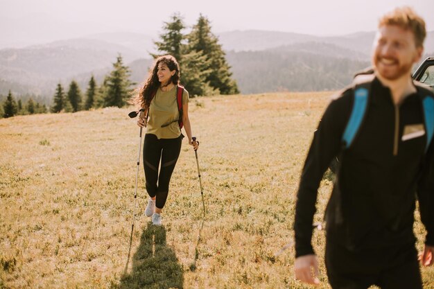 Smiling couple walking with backpacks over green hills