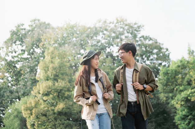 Smiling couple walking with backpacks over natural background.