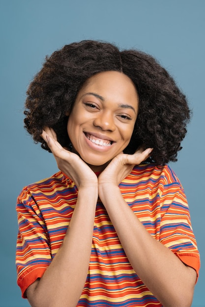 Smiling curly haired African American woman touching his face looking at camera