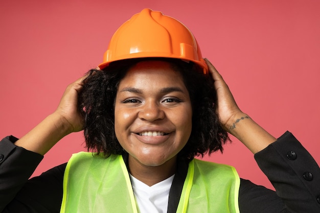 Smiling curly woman in helmet on pink background