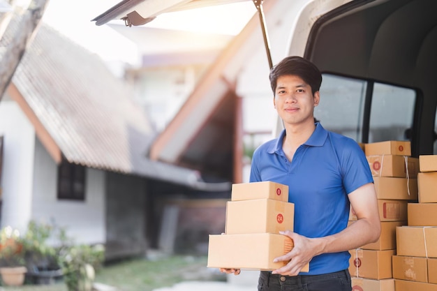 Smiling delivery asian man standing in front of his van Portrait of courier delivering parcel package