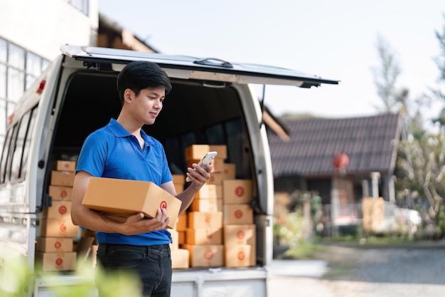 Smiling delivery asian man standing in front of his van Portrait of courier delivering parcel package