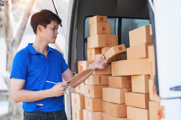 Smiling delivery asian man standing in front of his van Portrait of courier delivering parcel package