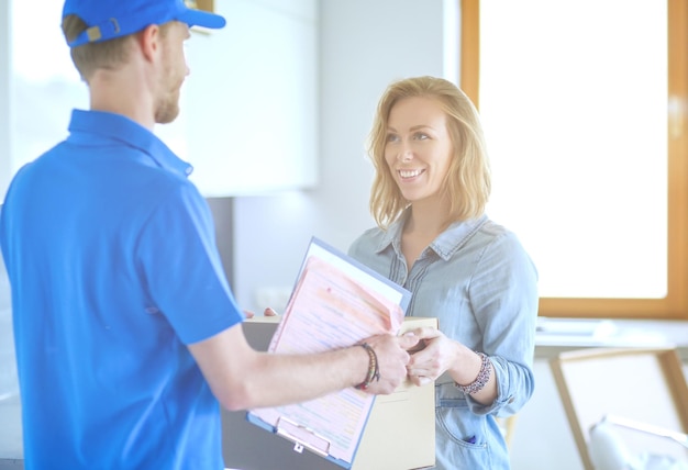 Smiling delivery man in blue uniform delivering parcel box to recipient courier service concept Smiling delivery man in blue uniform