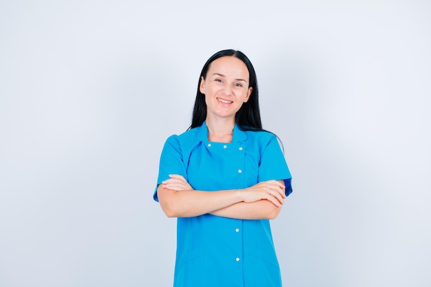 Smiling doctor is looking at camera by crossing arms on white background