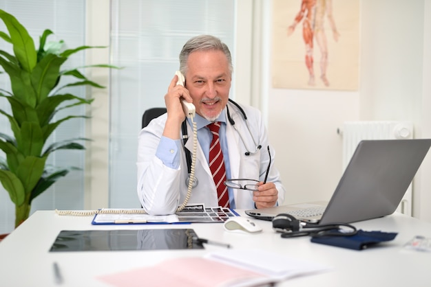 Smiling doctor talking on the phone in his office