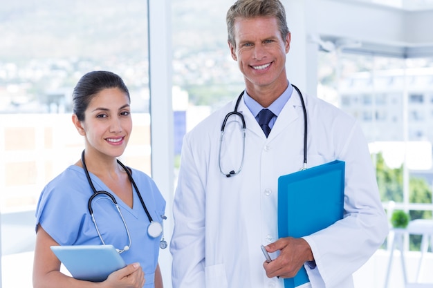 Smiling doctors looking at camera and holding clipboards 