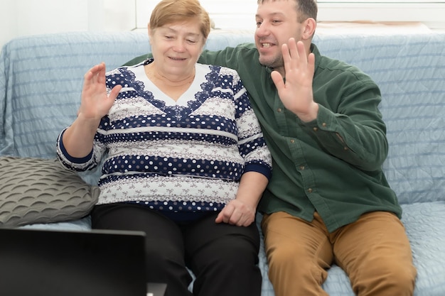 A smiling elderly woman and a man at home are sitting on the couch Positive emotions Technologies