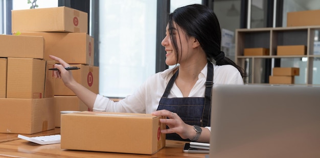 Smiling entrepreneur checking order on delivery box on work desk at home