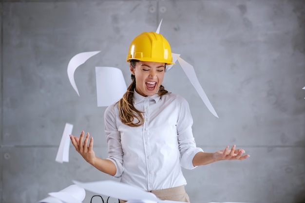 Photo smiling excited female architect with helmet on head finished her job on time.