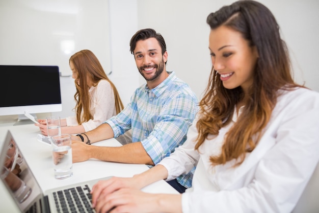 Smiling executive using laptop and digital tablet in conference room