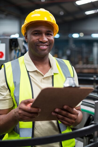 Smiling factory worker holding clipboard in factory