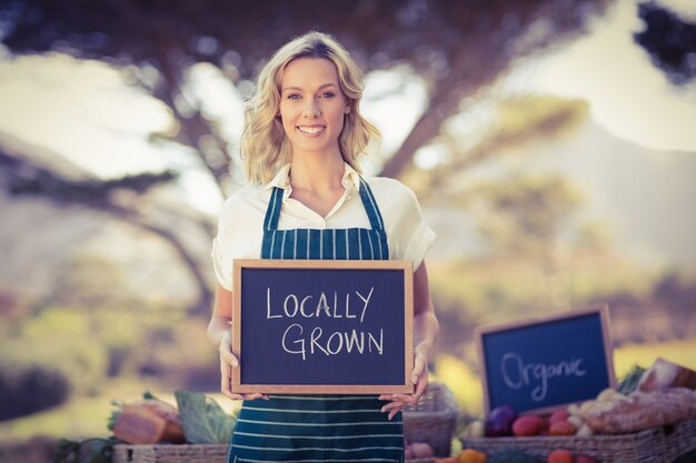 Photo smiling farmer woman holding a locally grown sign