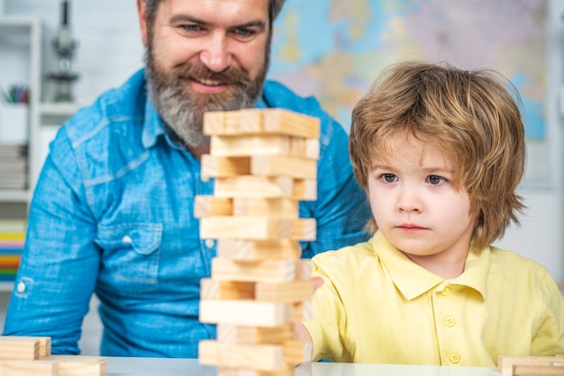 Smiling father and focused son playing jenga game at home individual tutoring elementary school