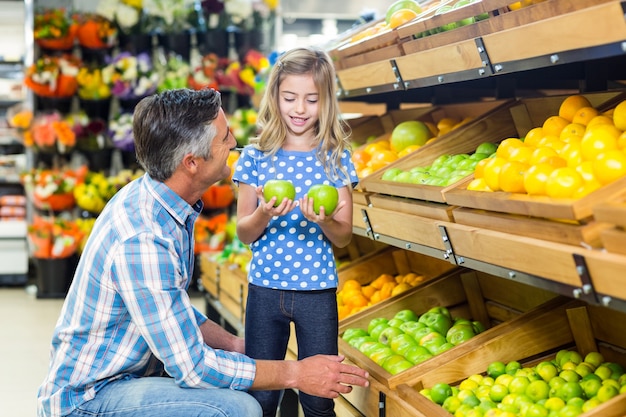 Smiling father giving apples to his cute daughter