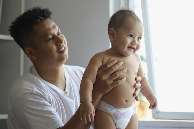 Smiling father holding cute baby boy, adorable baby is standing using diaper