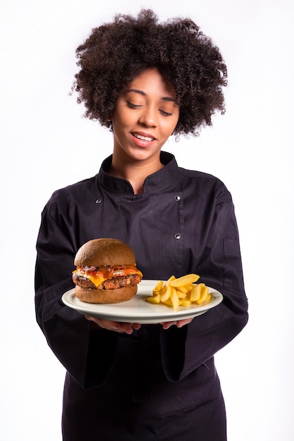 smiling female chef holding plate with burger and fries