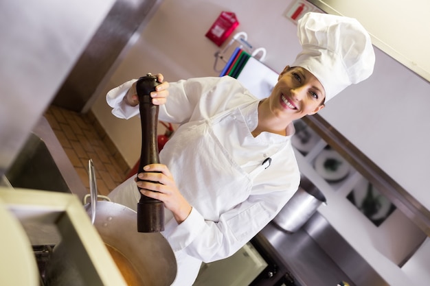 Smiling female cook preparing food in kitchen