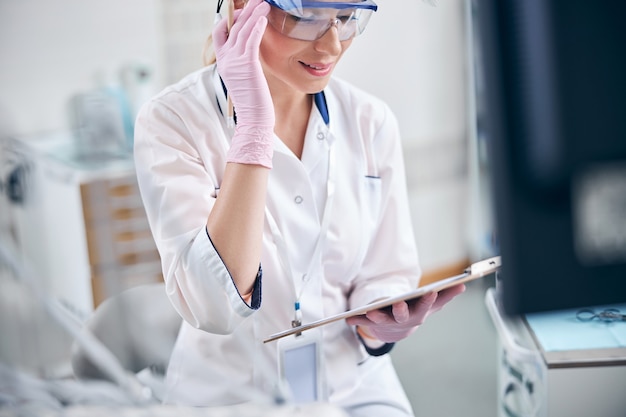 Smiling female dentist with clipboard in office