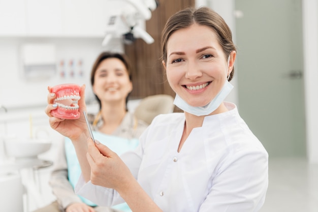 A smiling female dentist with dentures in her hands. In the dentistry's office