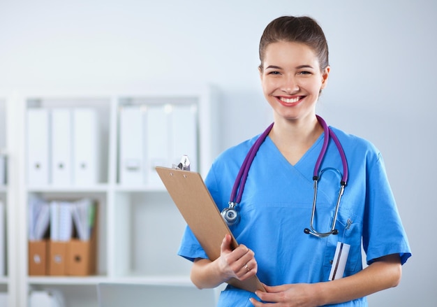 Smiling female doctor with a folder in uniform standing at hospital