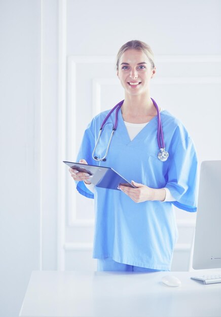 Smiling female doctor with a folder in uniform standing