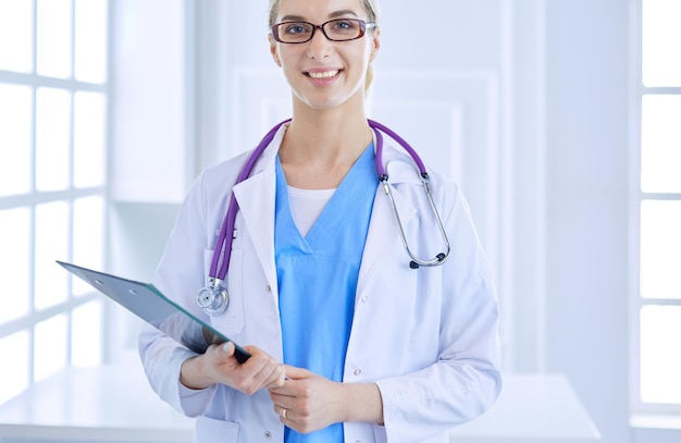 Smiling female doctor with a folder in uniform standing