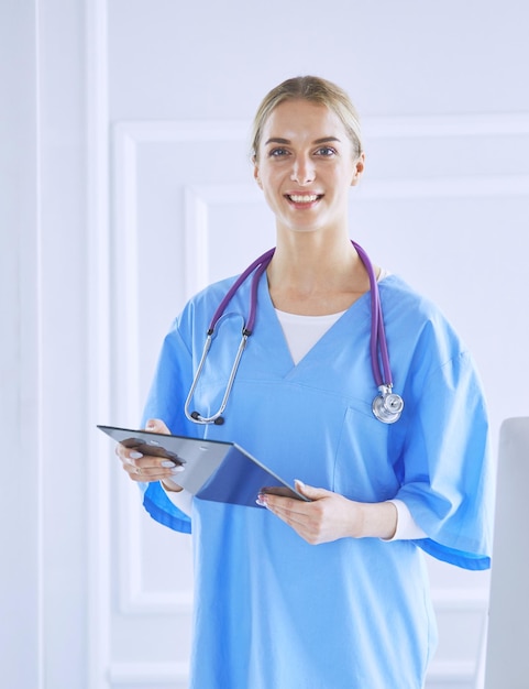 Smiling female doctor with a folder in uniform standing